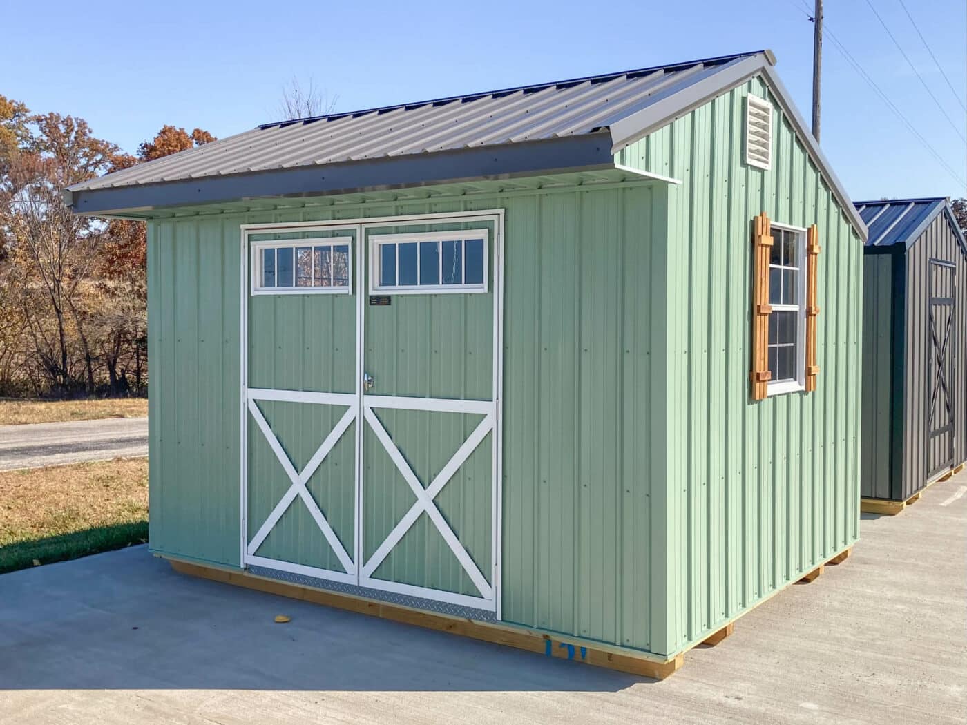 green shed built by Premier Barns with wooden shutters and classic double doors