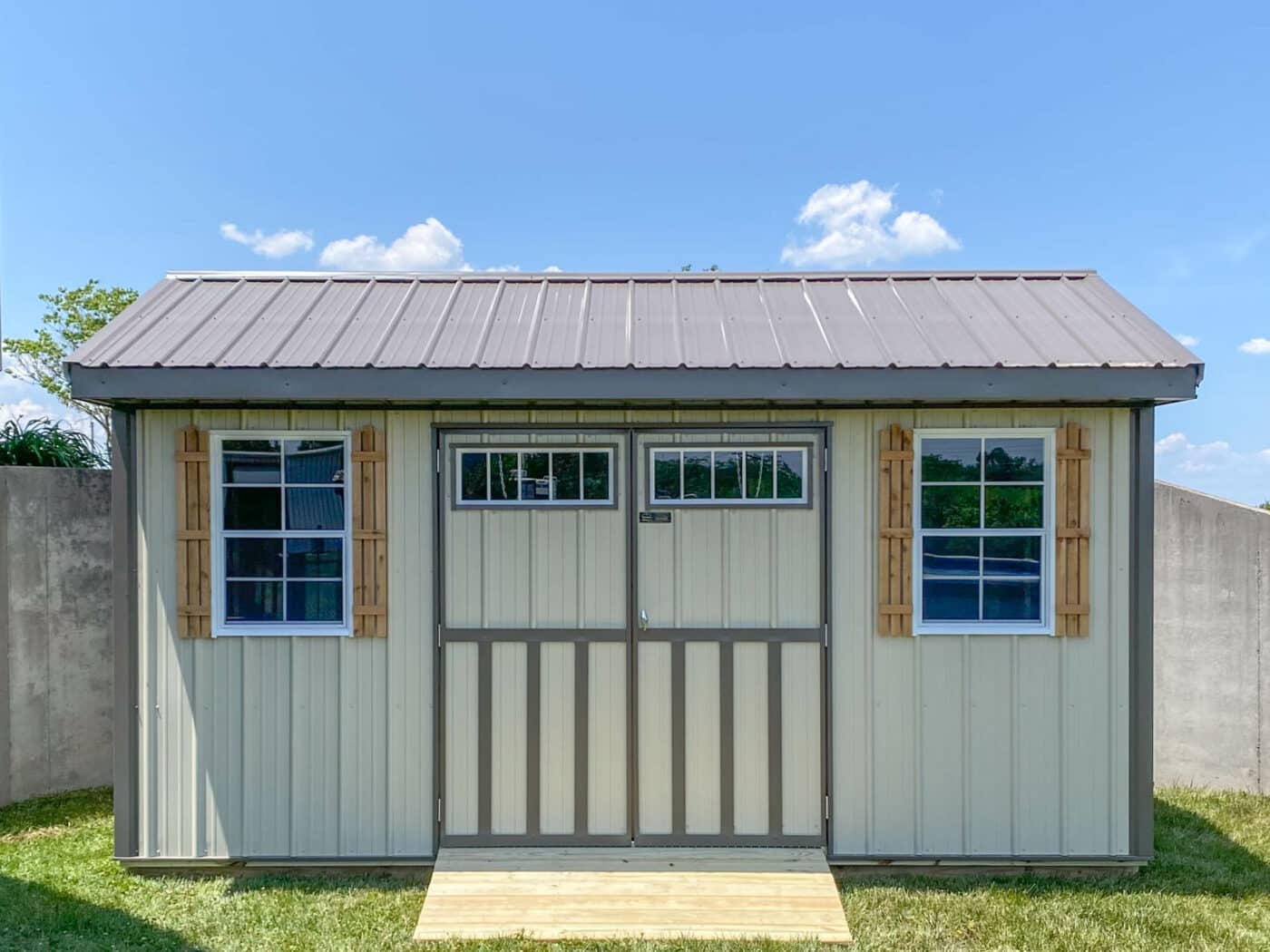 garden shed built by Premier Barns with wood shutters and tan siding