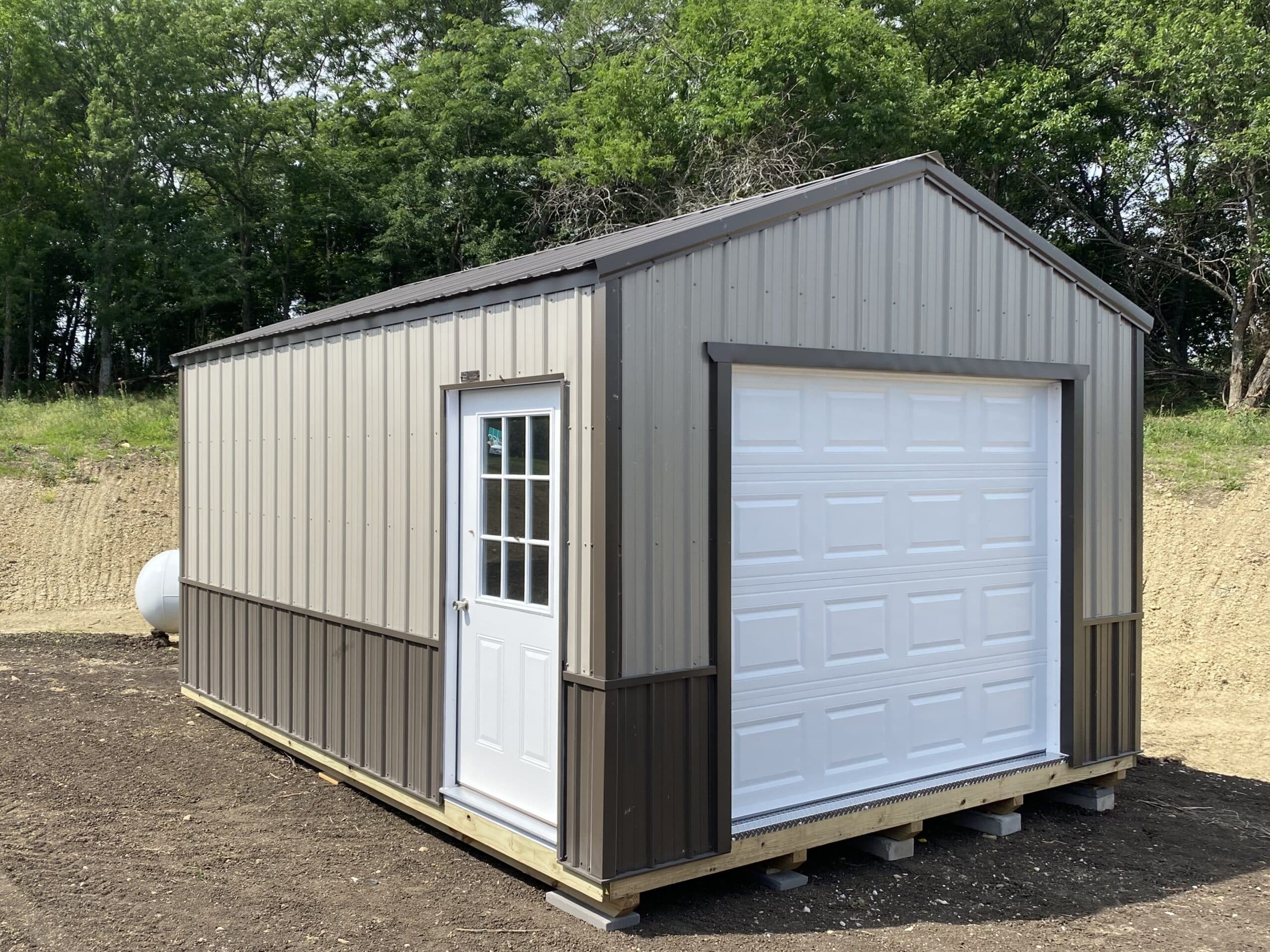 metal beige and brown garage shed with a white garage door and a side entrance door for sale near Olathe KS